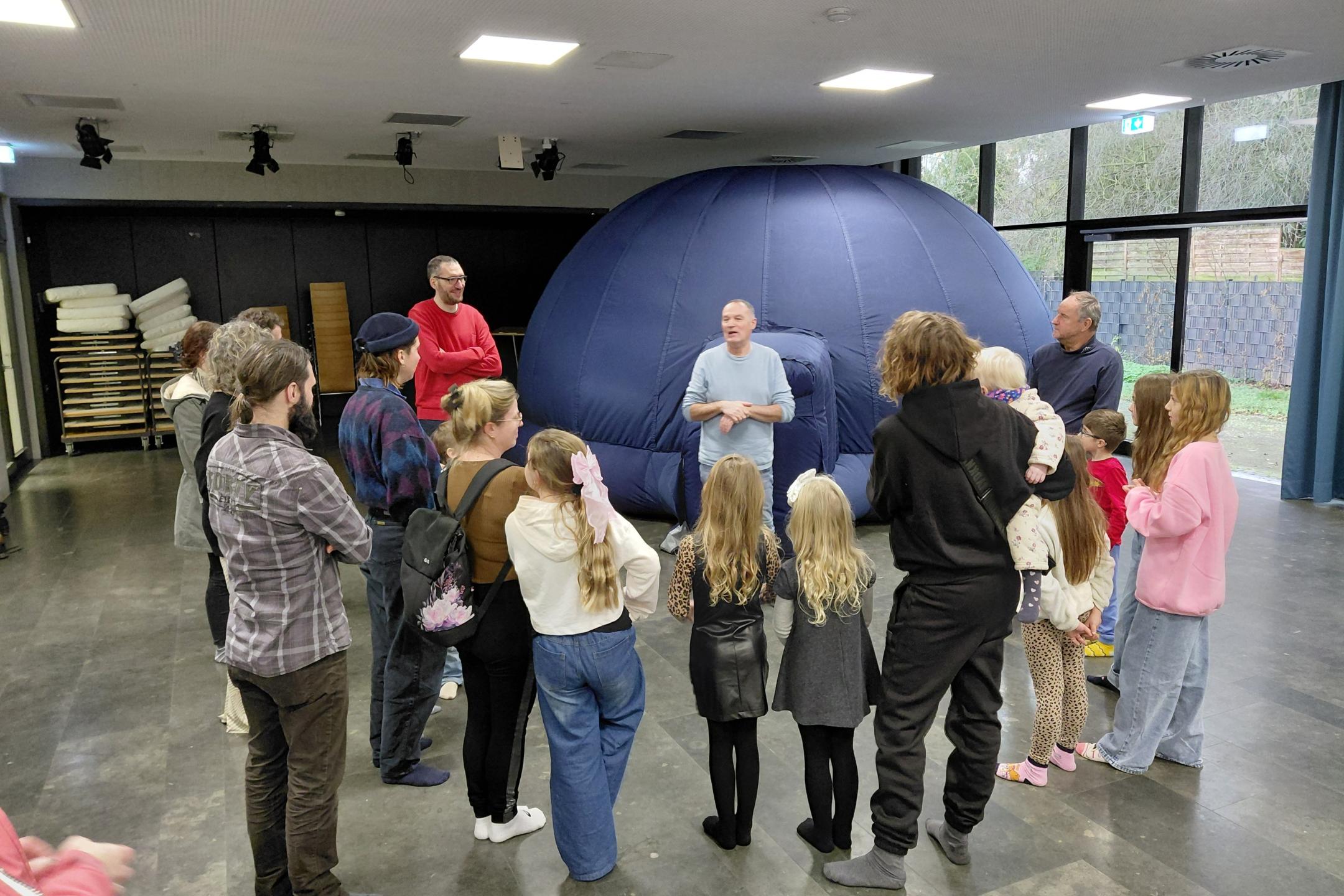 eine Gruppe Kinder und Erwachsener vor einem aufblasbaren Kuppelzelt