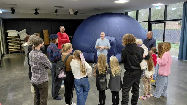 eine Gruppe Kinder und Erwachsener vor einem aufblasbaren Kuppelzelt