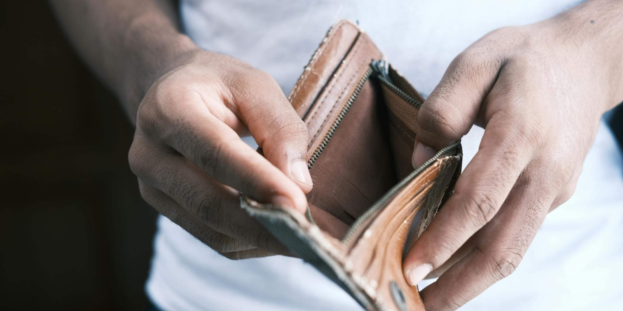 Ein Mensch hält eine leere Geldbörse in den Händen