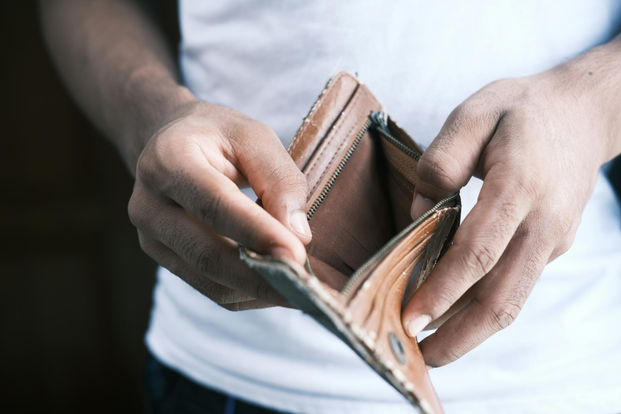 Ein Mensch hält eine leere Geldbörse in den Händen