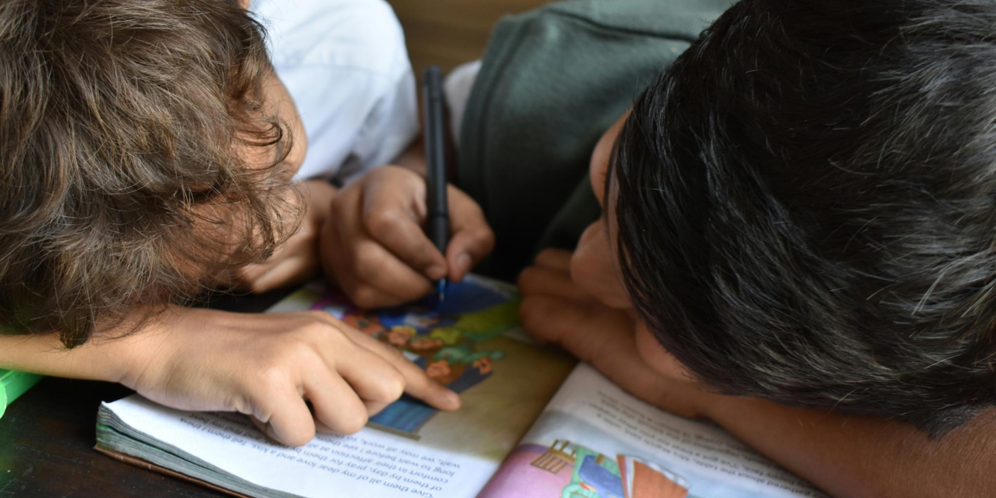 zwei Kinder schreiben in ein Buch