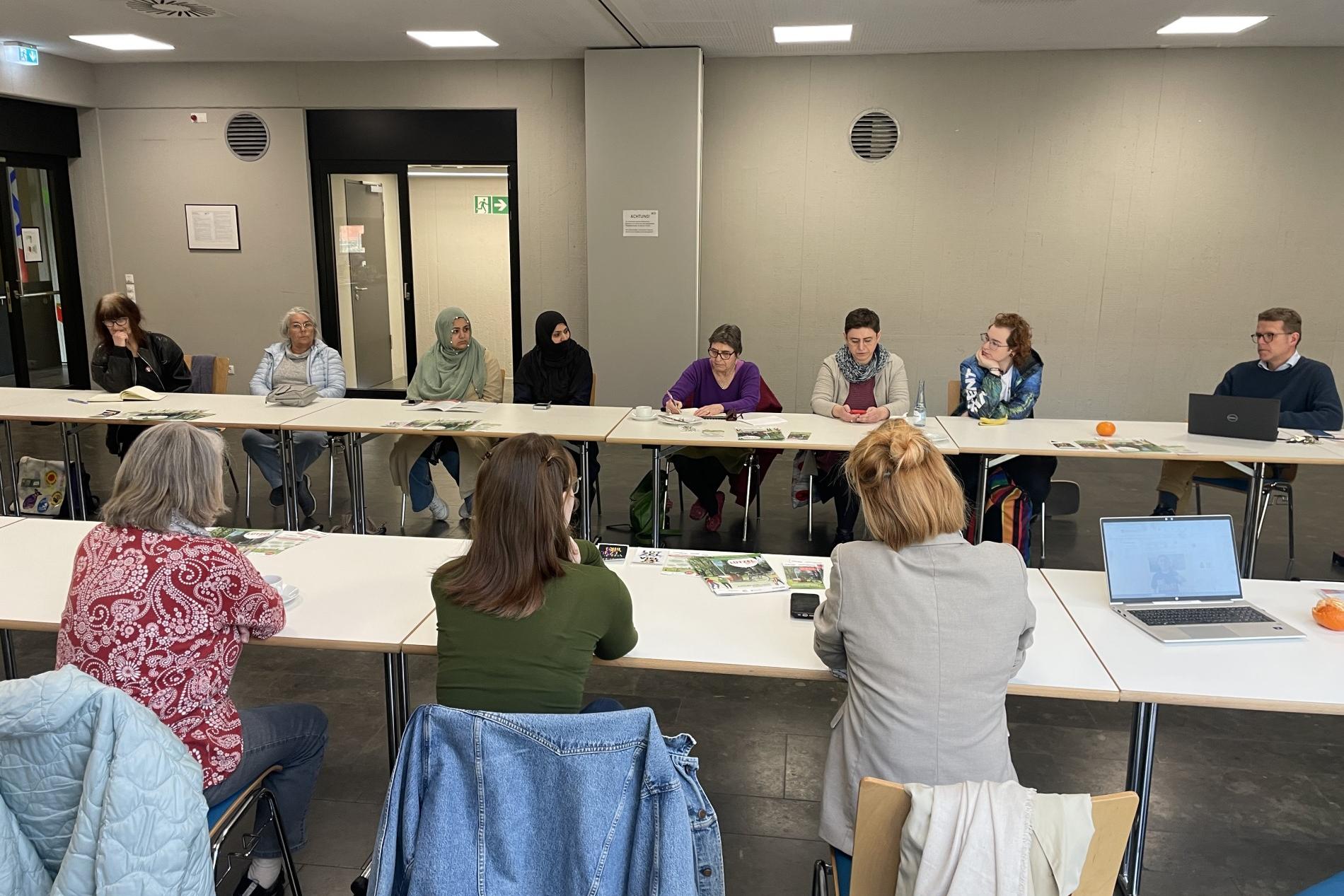 Personen sitzen an Tischen und diskutieren miteinander