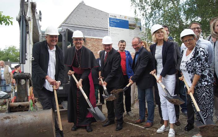 Menschen mit einem Spaten in der Hand stehen zusammen und eröffnen die Baustelle am Bürgerzentrum