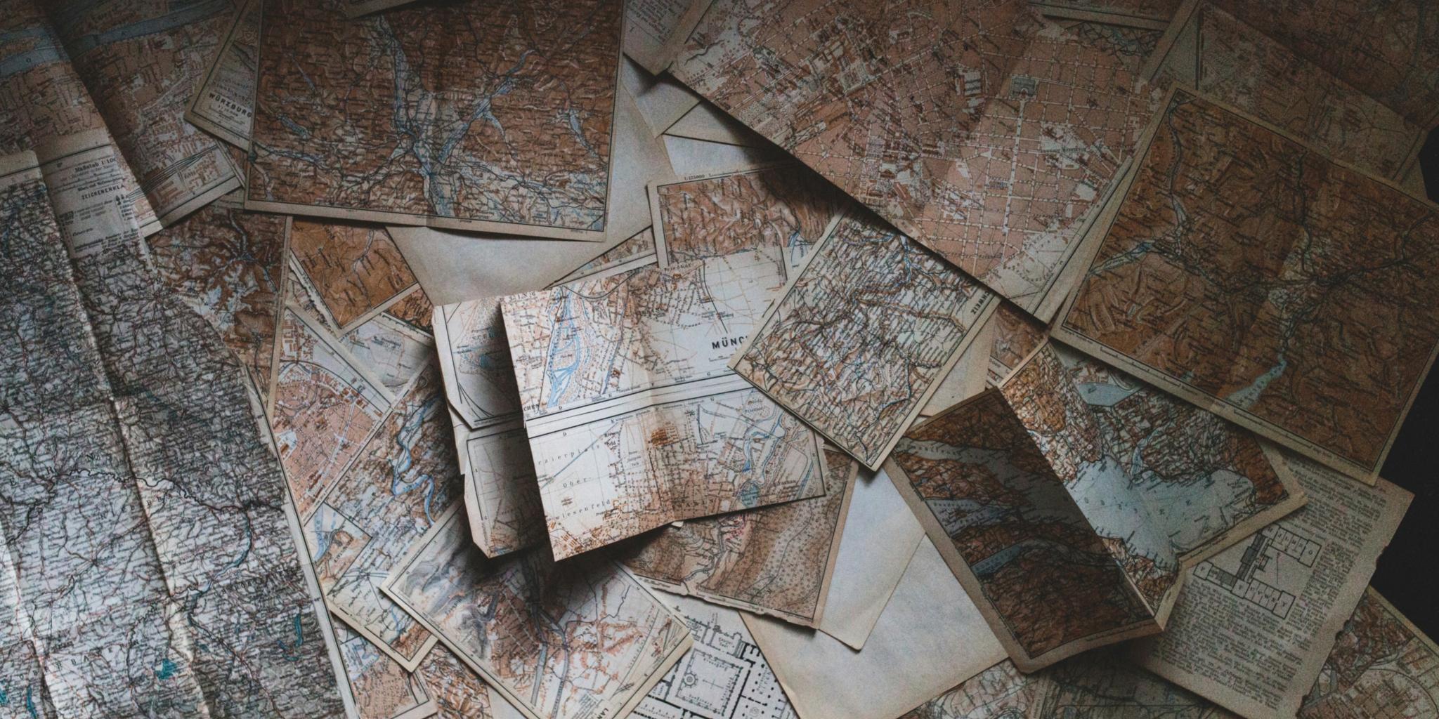 Historische Karten liegen verteilt auf einem Tisch (c) Andrew Neel auf Unsplash Historische Karten liegen verteilt auf einem Tisch