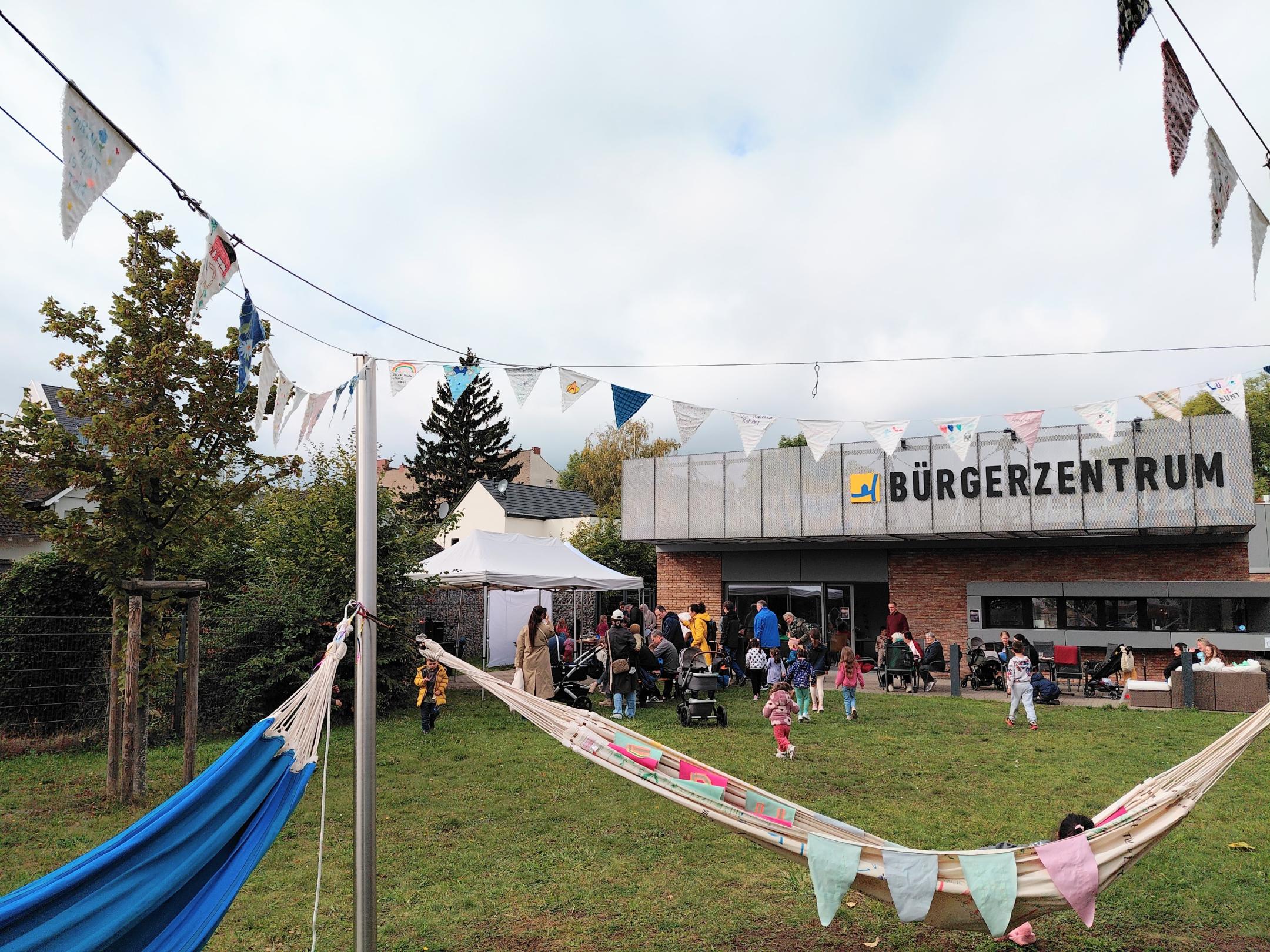 zu sehen ist die Wiese vor dem Bürgerzentrum Lützel, Hängematten und Menschen, die dort zusammen sind.