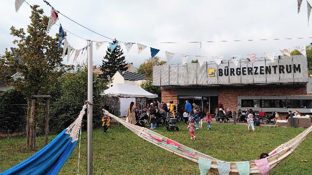 zu sehen ist die Wiese vor dem Bürgerzentrum Lützel, Hängematten und Menschen, die dort zusammen sind.
