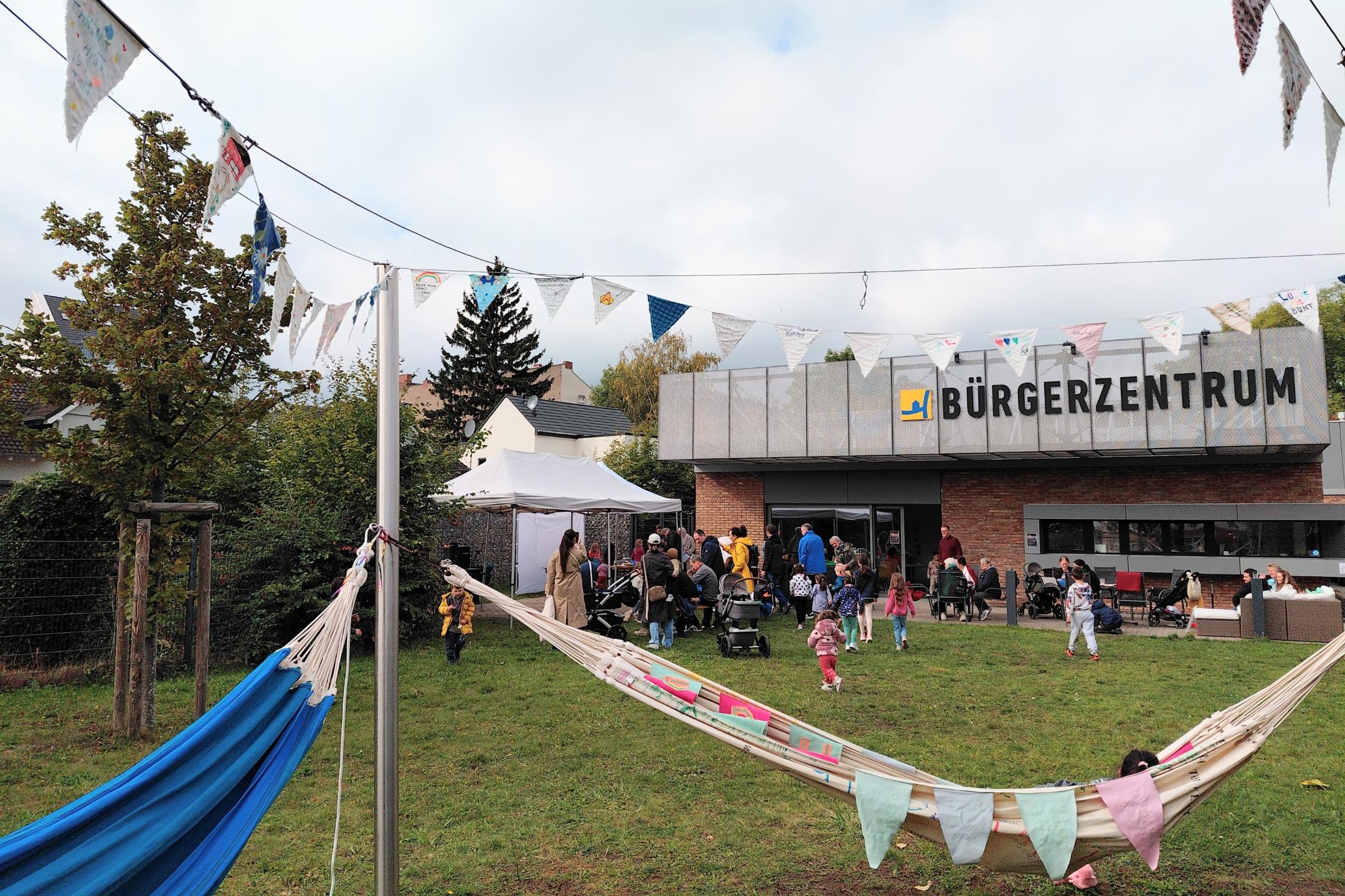 zu sehen ist die Wiese vor dem Bürgerzentrum Lützel, Hängematten und Menschen, die dort zusammen sind.