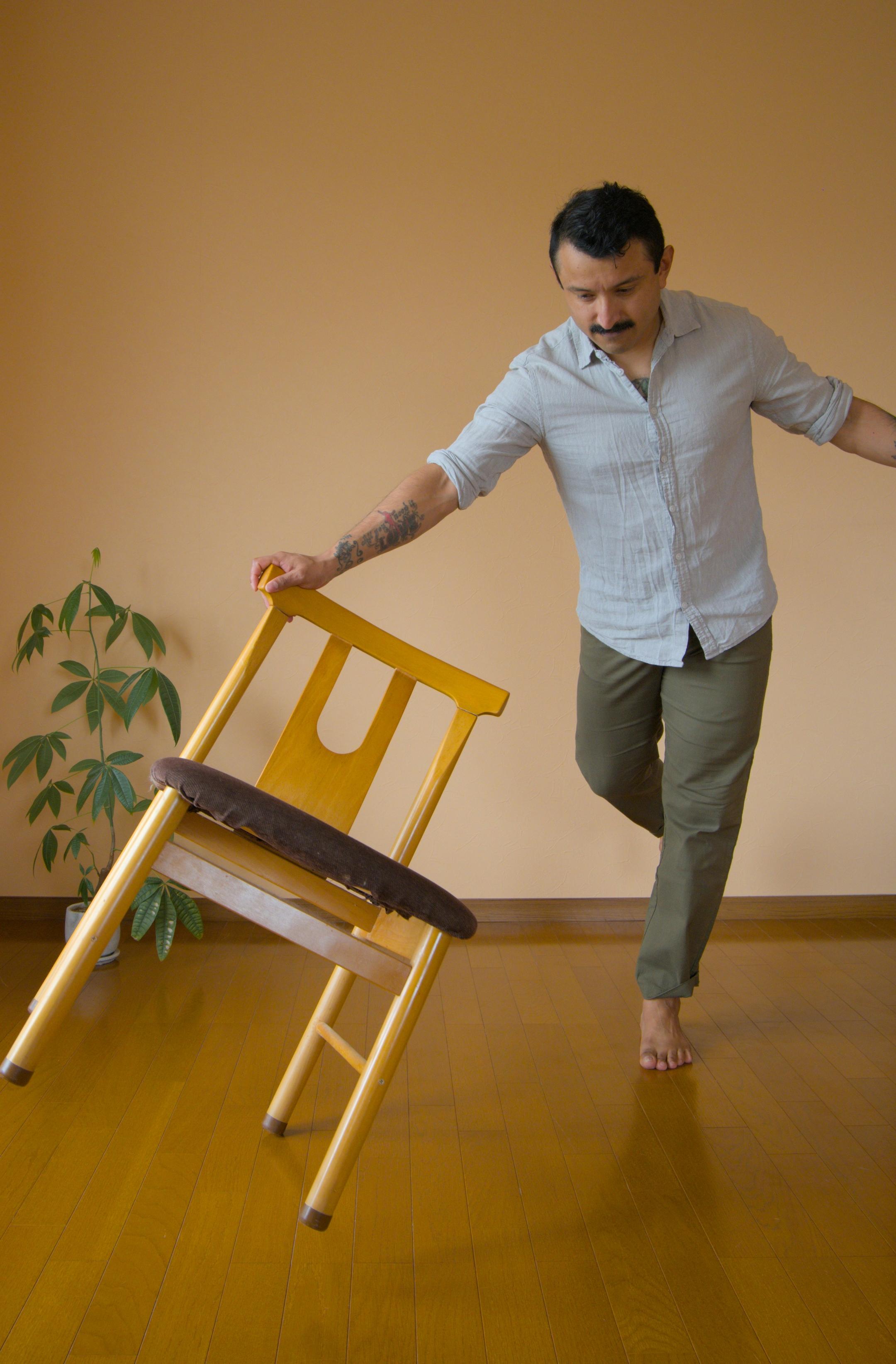 Ein Mann balanciert mithilfe eines Stuhles