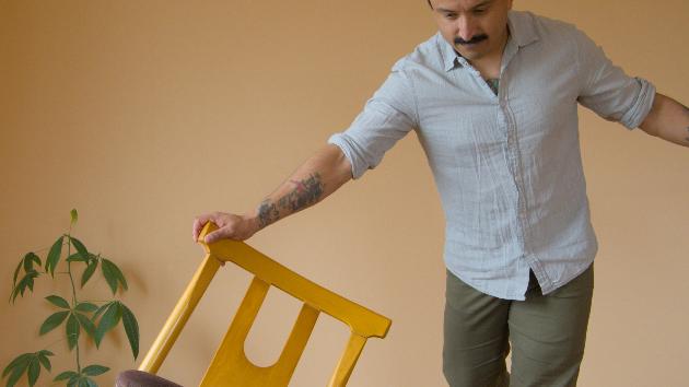 Ein Mann balanciert mithilfe eines Stuhles