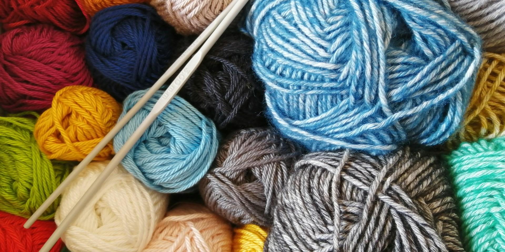 Foto von bunten Wollknäueln mit Häkelnadeln